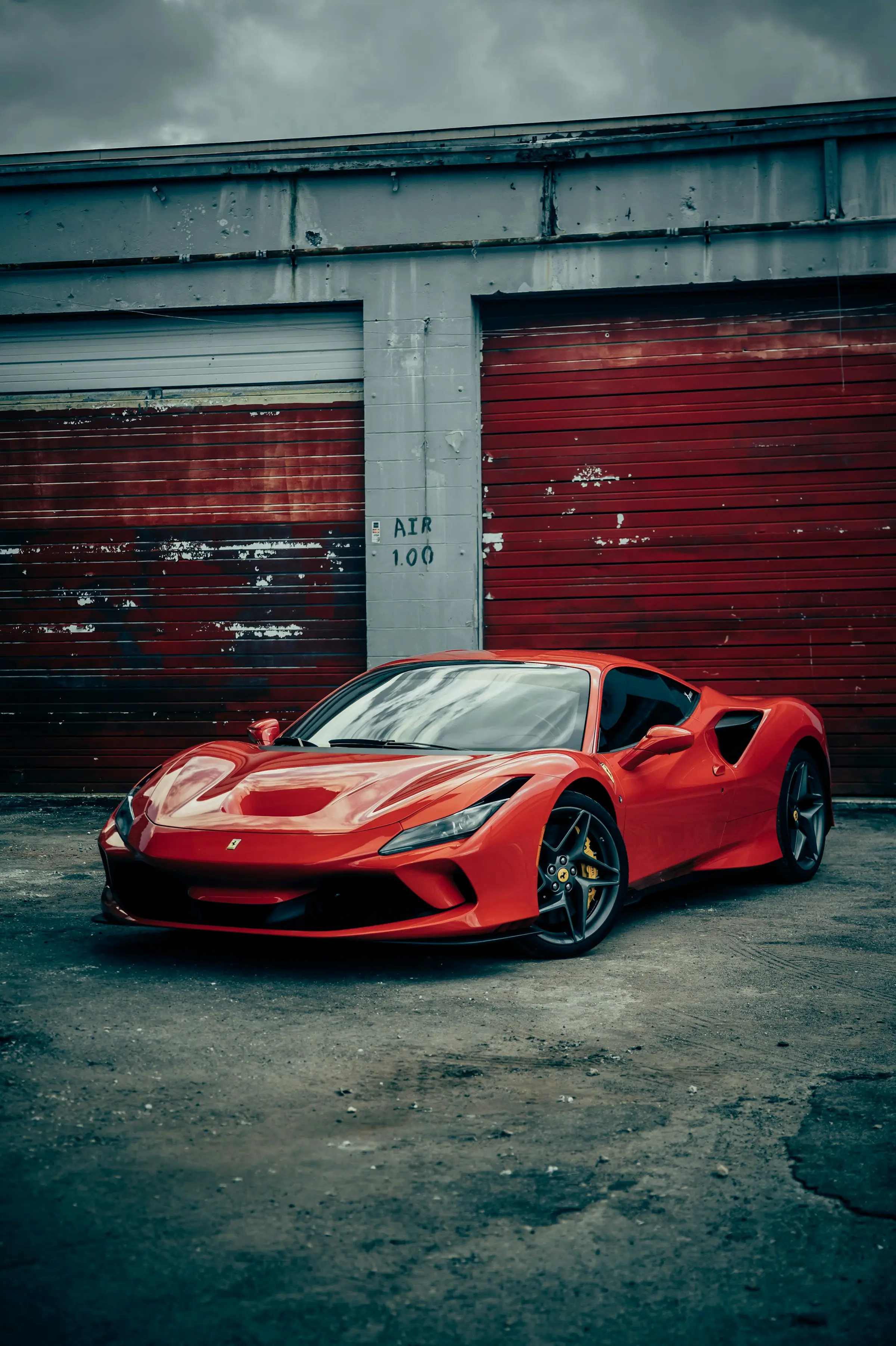 Red Ferrari F8 Tributo in front of weathered garage doors
