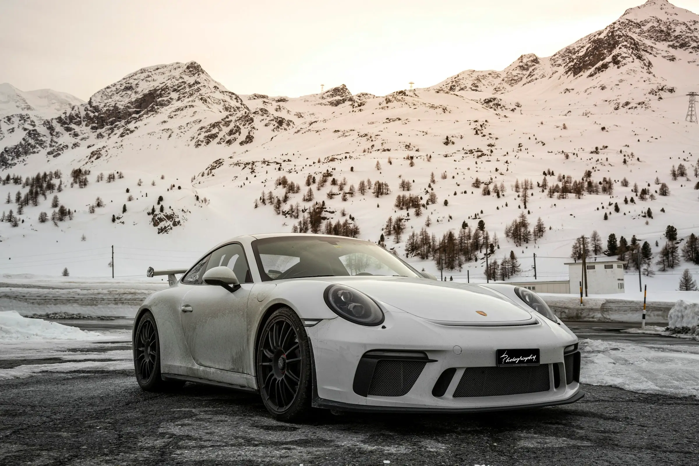 White Porsche 911 GT3 Touring in an alpine landscape with snow