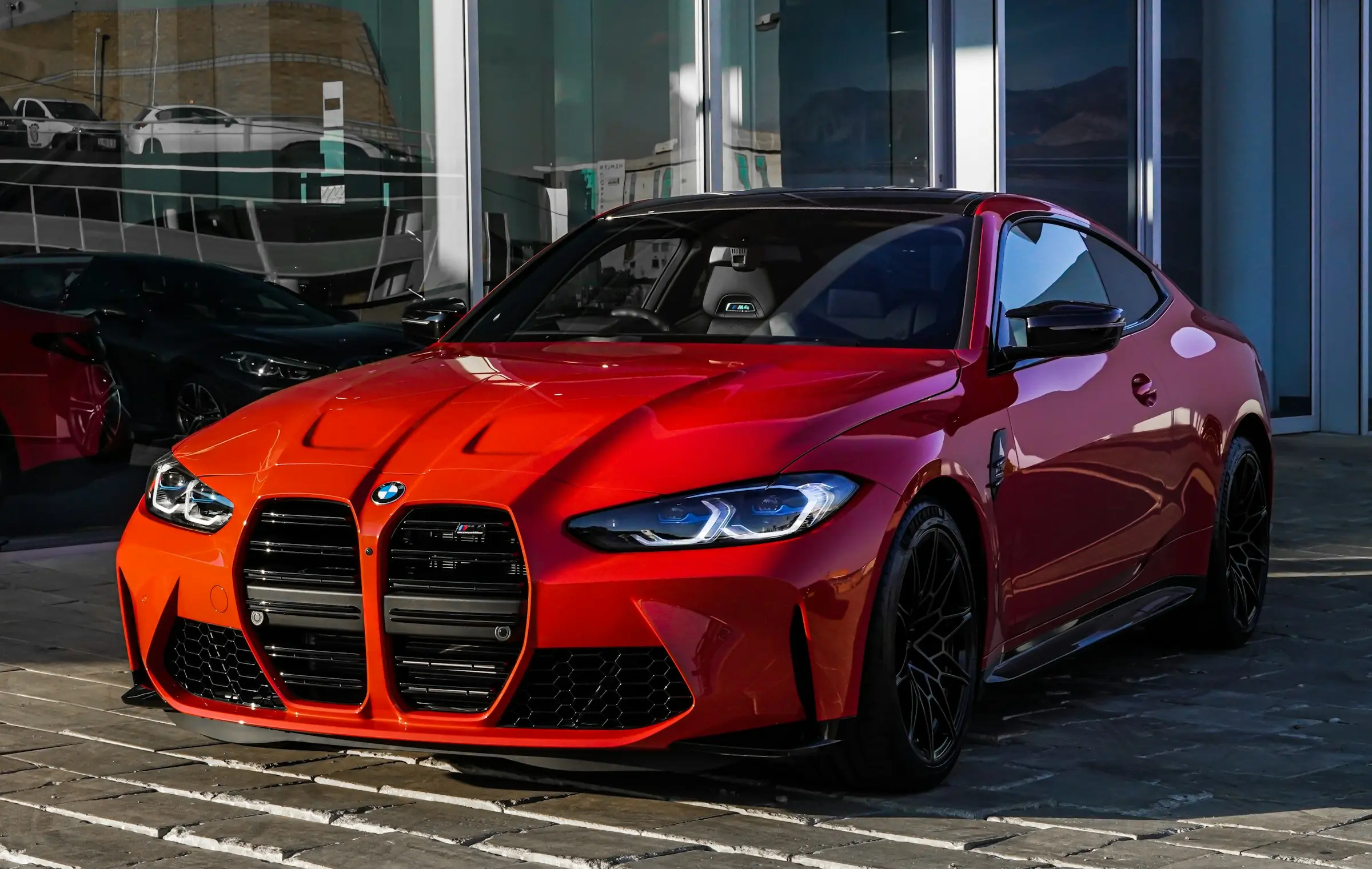 Red BMW M4 Competition outside a glass showroom
