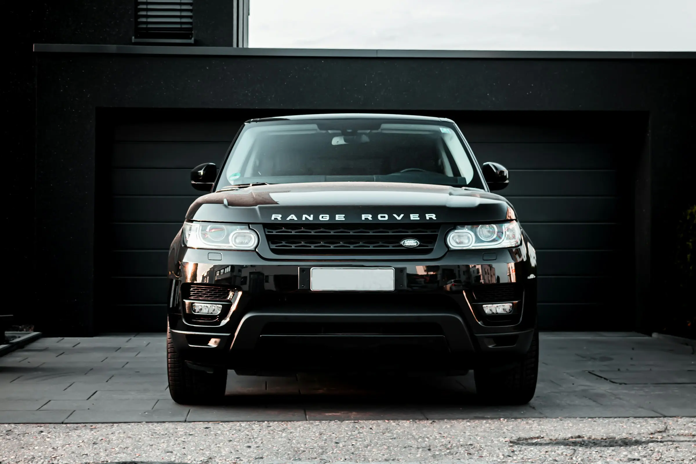 Black Range Rover Sport parked in front of a dark garage door