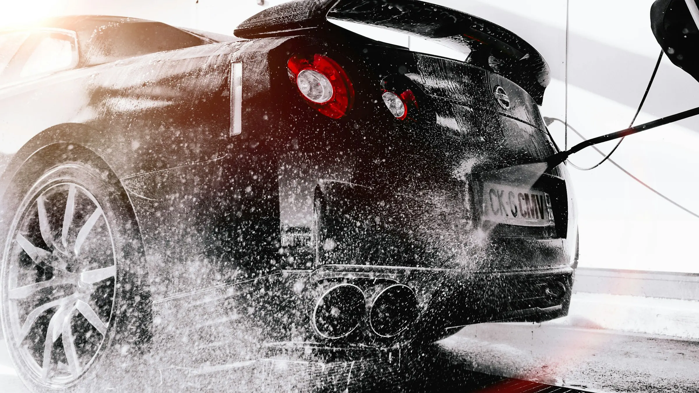 Water spraying across the rear of a dark sports car